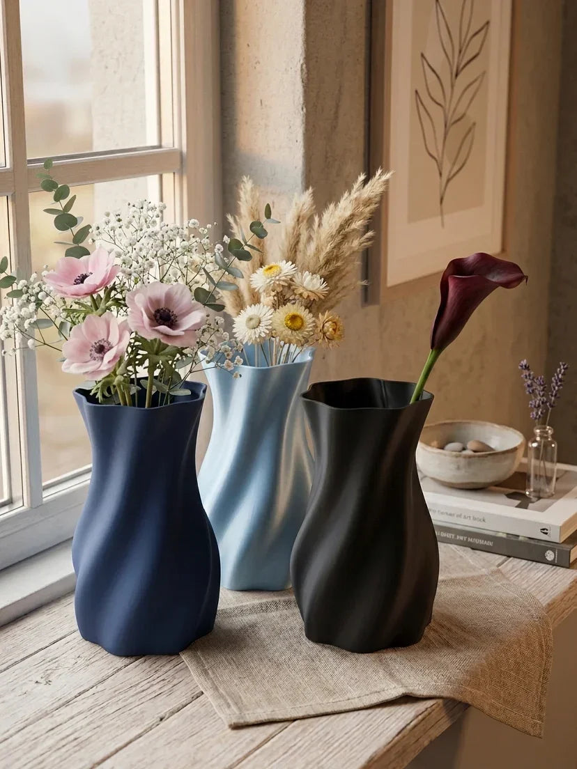 Stilfulde 3D-printede vase i blå, lyseblå og sort med blomster ved vindue